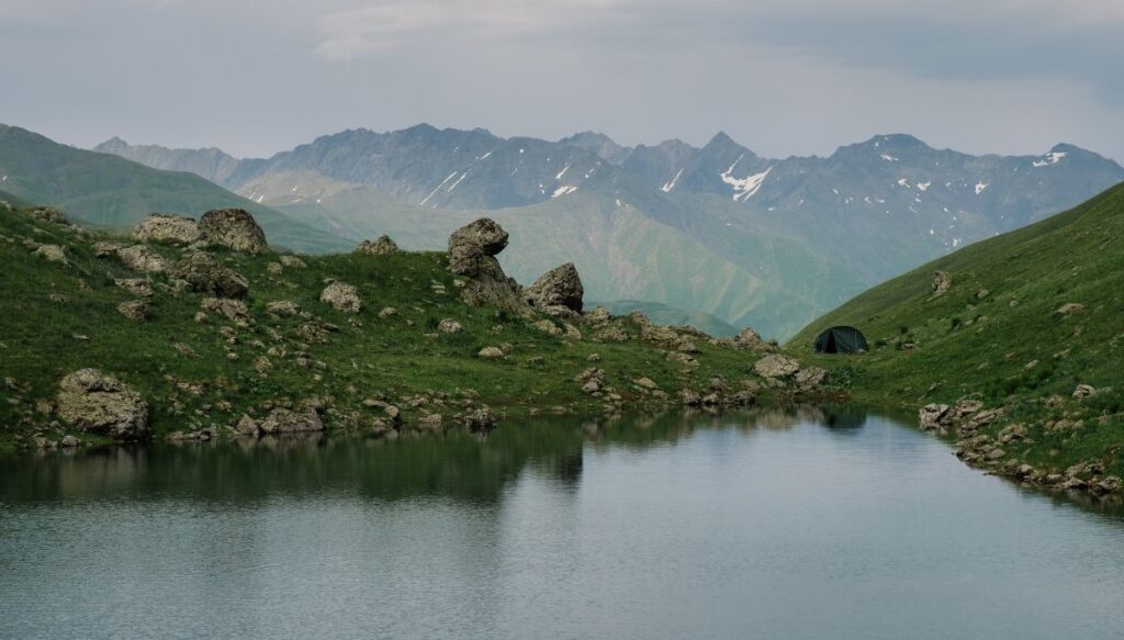 View of the Abudelauri Lakes with unique rock formations all along the lake and giant mountains off in the distance. 