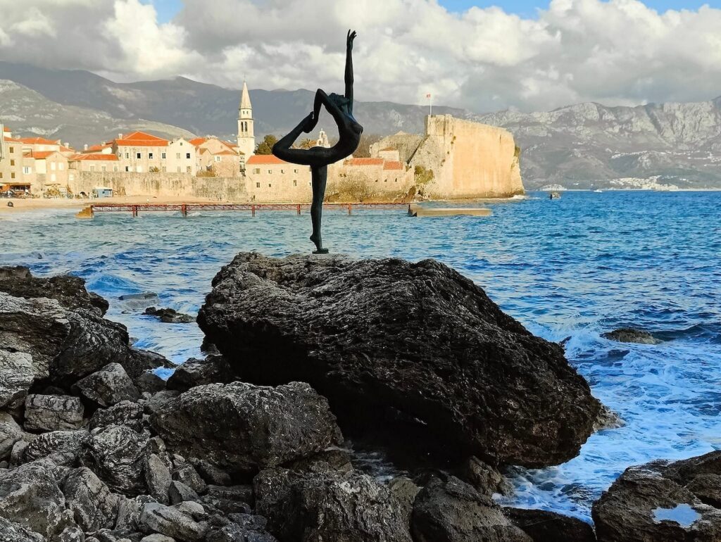 View of the dancer statue in Budva with the Old Town in the background. 