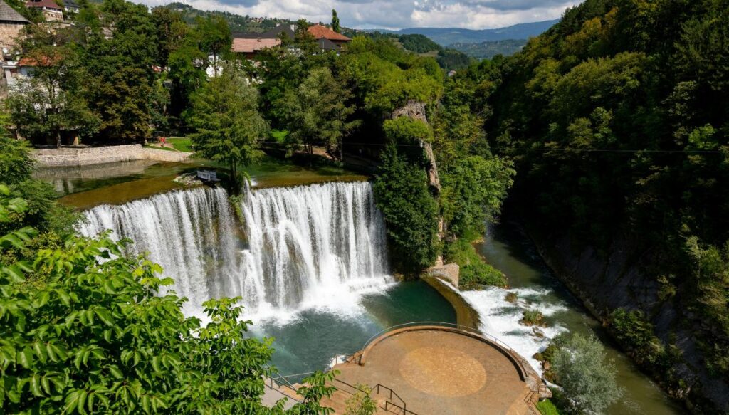 Aerial view of beautiful Pliva Waterfall in Jajce. You can see a round viewing platform and houses behind the waterfall.
