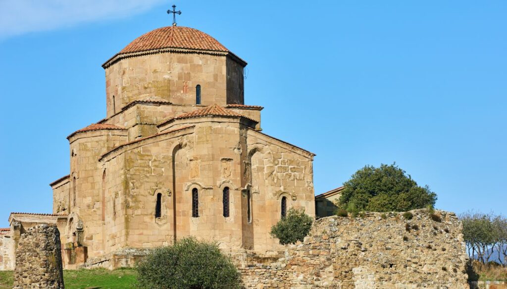 View of the stone church of Jvari Monastery with a stone wall all around it. 