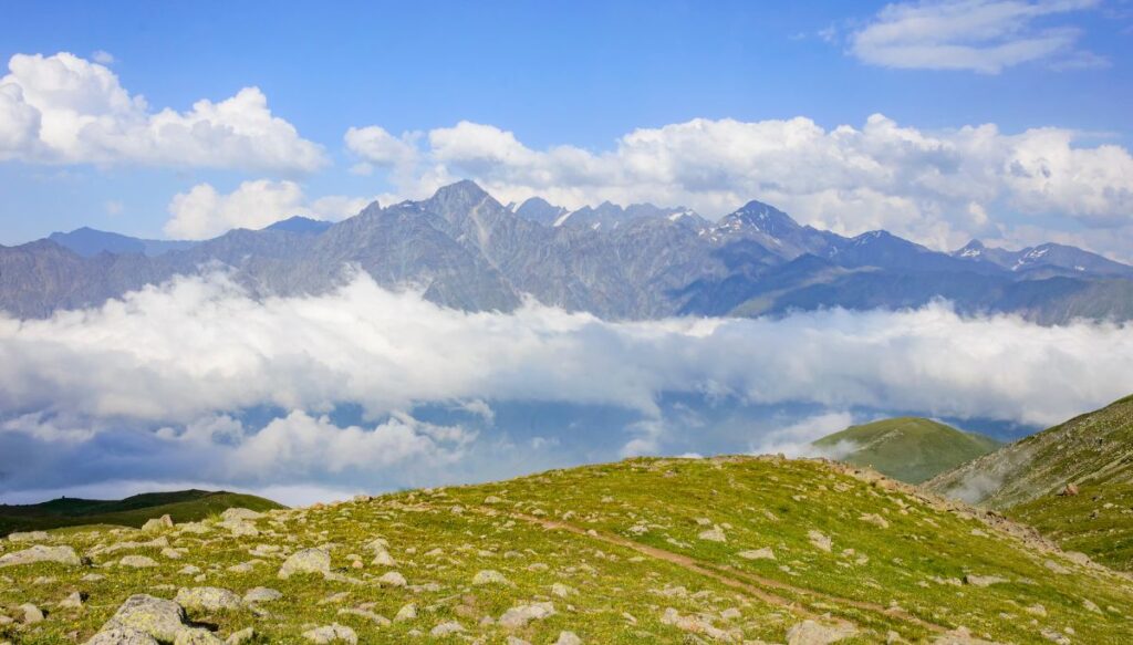 Sweeping panoramic view of the mountains and clouds inside of Kazbegi National Park. 