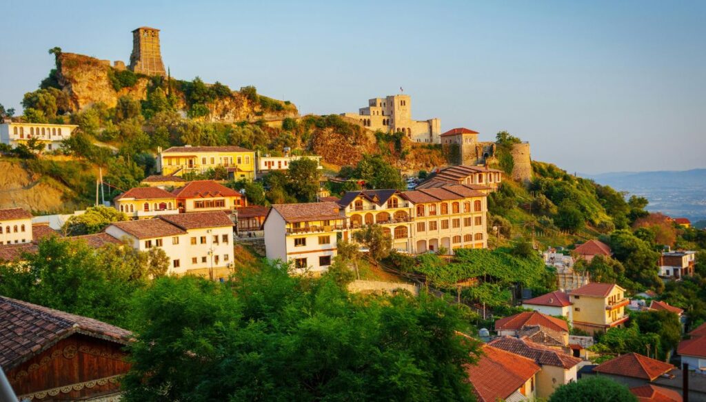 View of the white buildings and the castle in the background along a hill in Krujë at sunset.