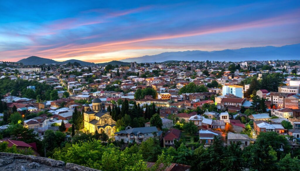 View from the church in Kutaisi of the city and the sun setting behind the mountains in the background. 
