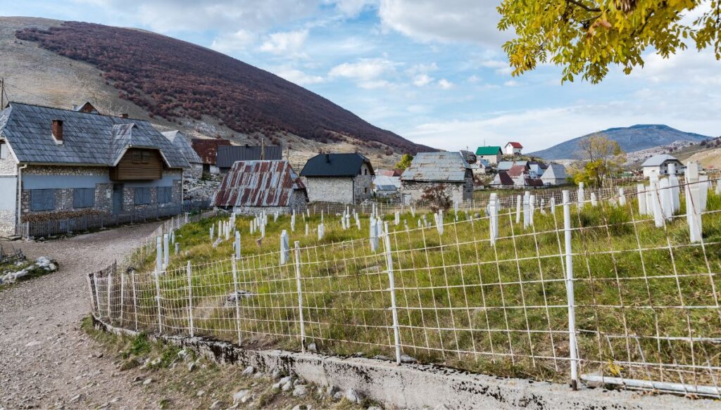 View of little cottage sitting along a stone path with a Muslim cemetery on the right in the town of Lukomir.