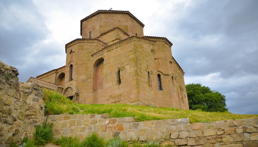 View of the stones of Samtavro Monastery in Mtskheta Georgia on a cloudy day with a stone wall in the front of the photo. 