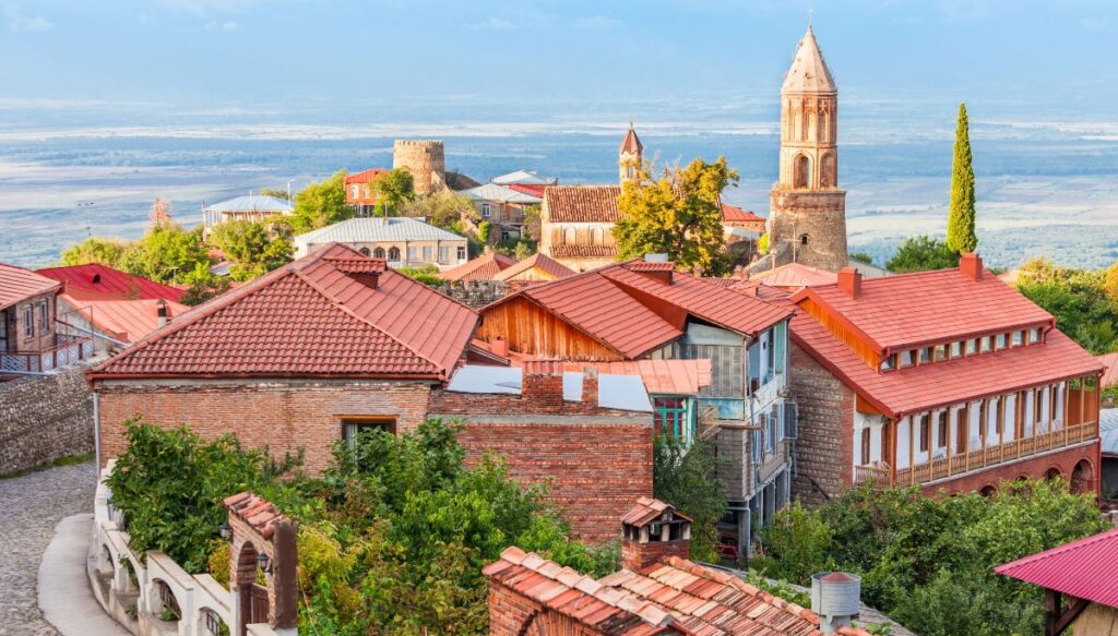 View ot the charming historic center of Sighnaghi with a church steeple and red roofed homes overlooking the surrounding mountains, 