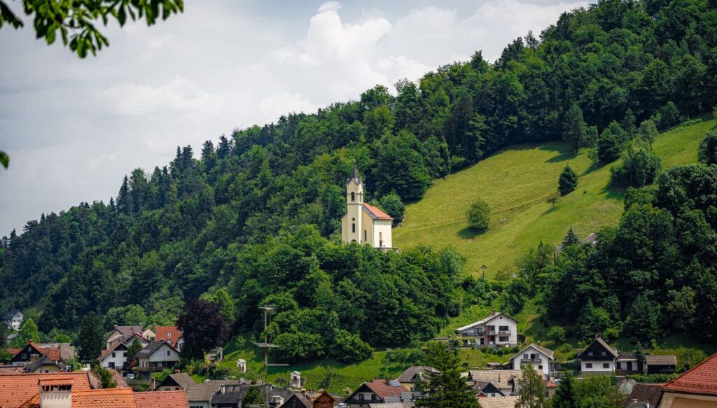 View of a white church sitting on a hill overlooking the town of Škofja Loka in Slovenia.