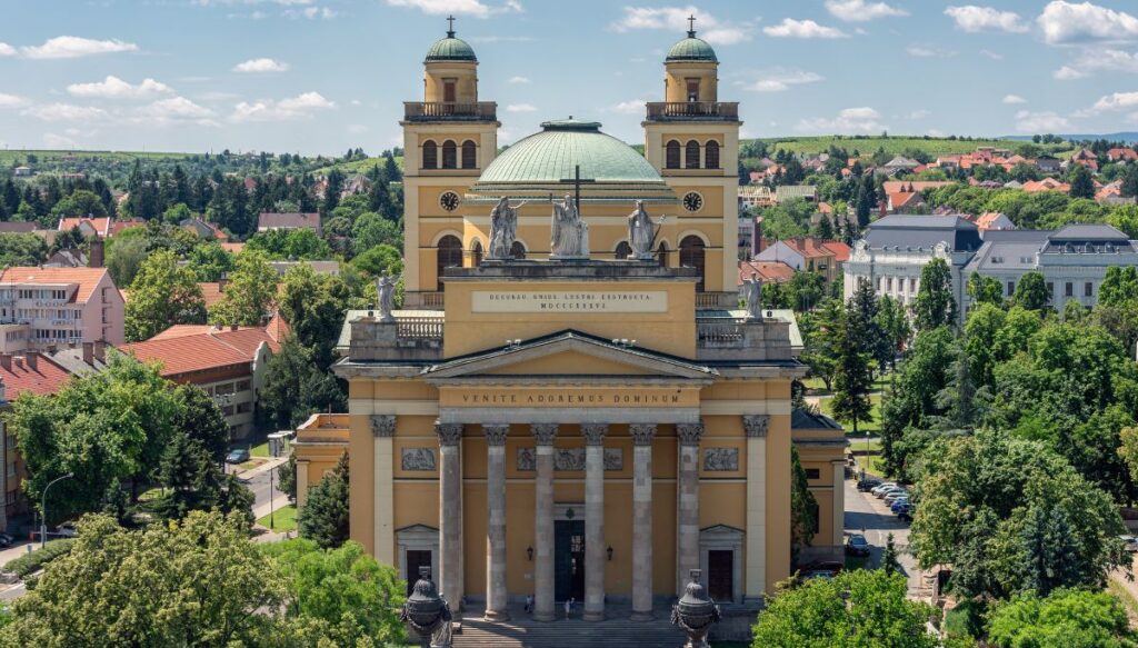 View of a yellow Cathedral with two towers and roman columns out front in Eger. This one of the most beautiful places in Hungary.