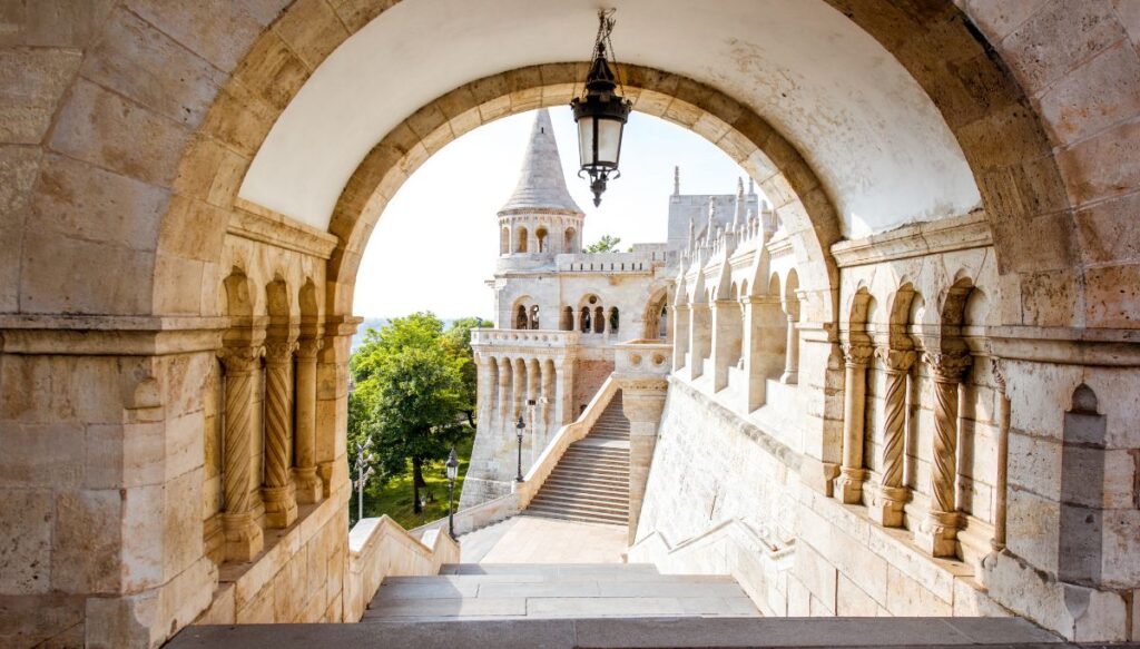 View of the turrets and white marble that makes up the stairs and towers of Fisherman's Bastion. This photo looks through a coridor and shows you the exterior.