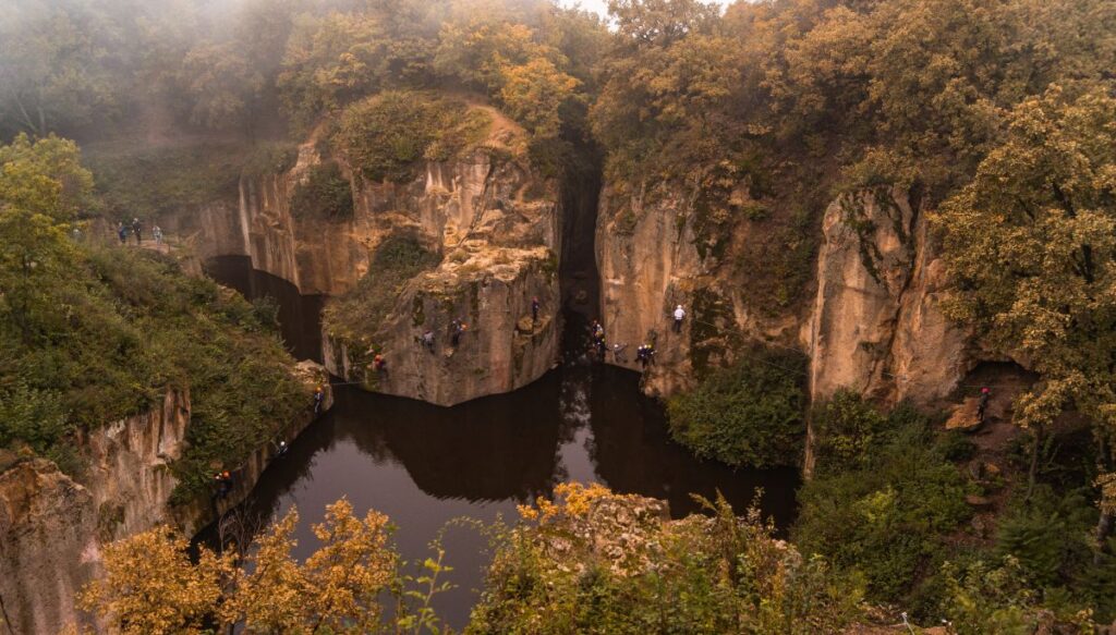 View of the steep cliffs and yellow trees surrounding Megyer-hegyi Tarn in Hungary in Autumn.