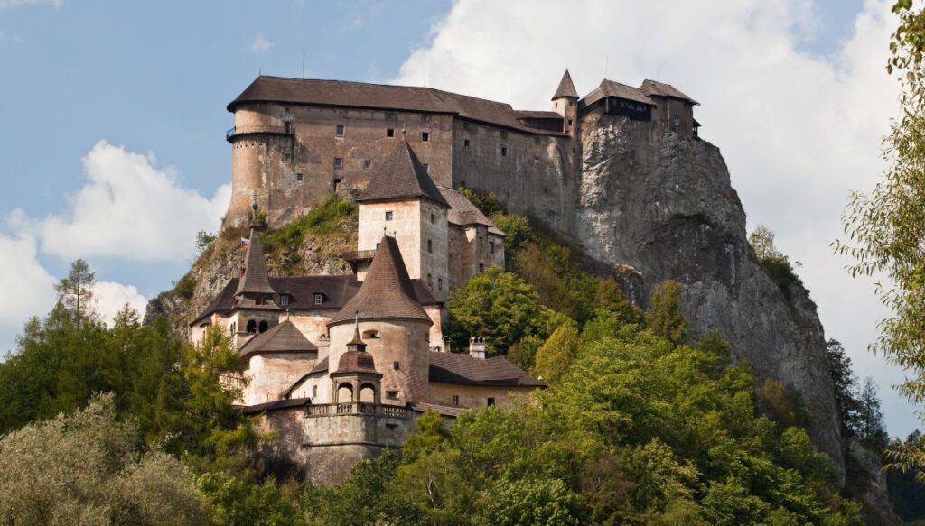 View of a stone castle with a brown roof built into the stones on a cliff at Orava Castle.