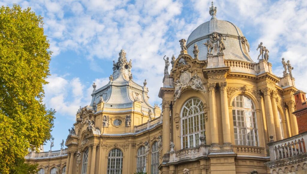 View of the yellow exterior and blue roofs of the Baroque-style Vajdahunyad Castle in Hungary.